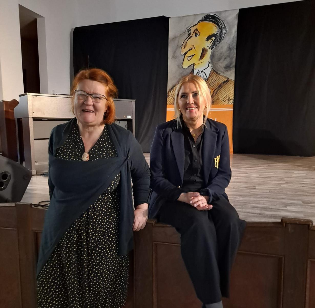 Katarzya Błaszczak i Dorota Cukiernik uśmiechnięte stoją przed sceną 