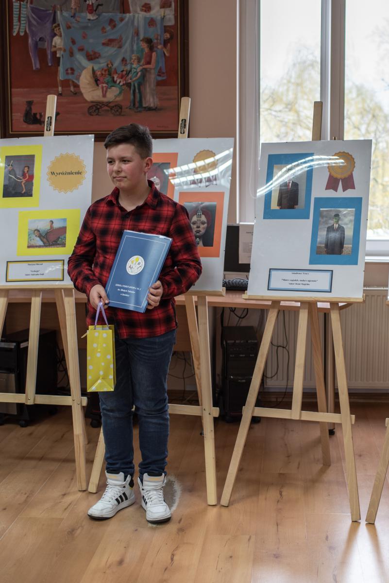 Amadeusz Tracz  stoi przy swoich pracach. Powiększ zdjęcie 