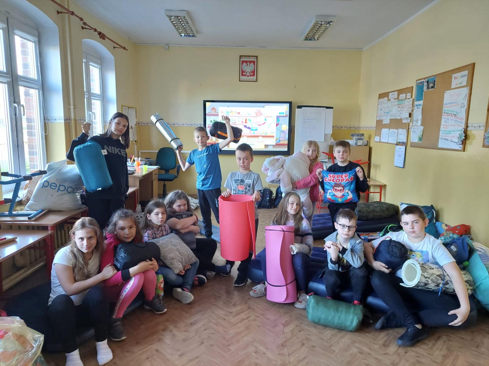 Dzieci z karimatami i śpiworami siedzę w klasie 