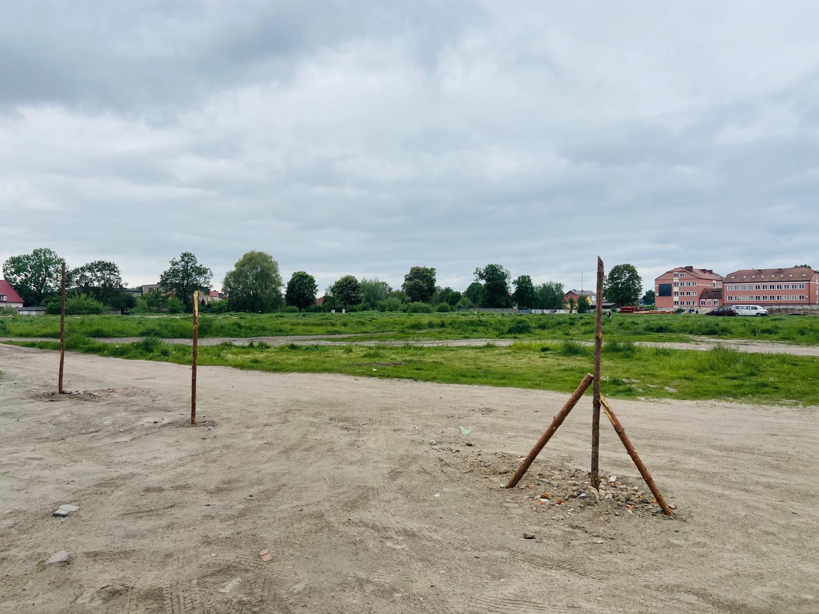 Pusty plac, przygotowane słupki drewniane na ogrodzenie. 