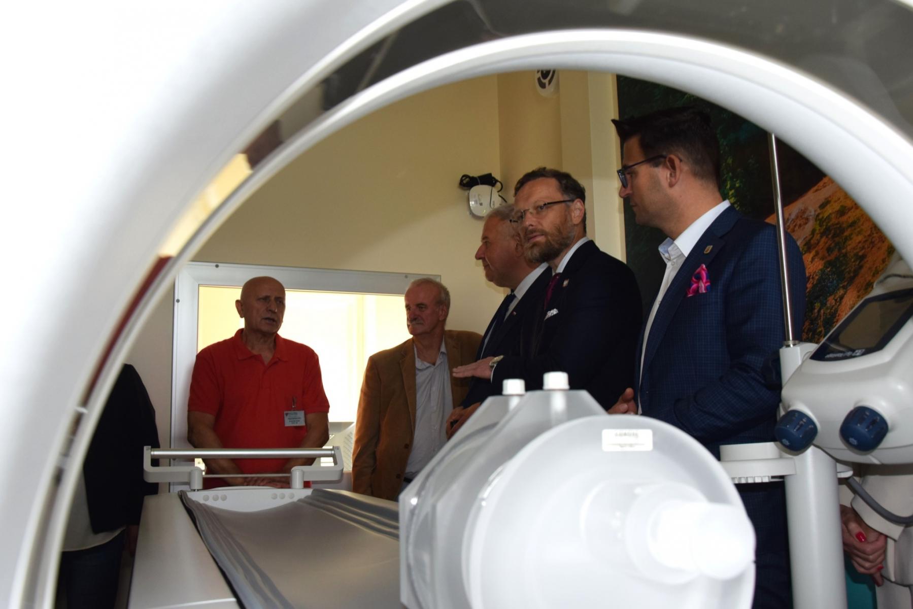 Tomograf, w okienku widać pięciu rozmawiających mężczyzn 