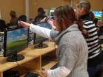 Uczniowie stoją przed monitorami komputera