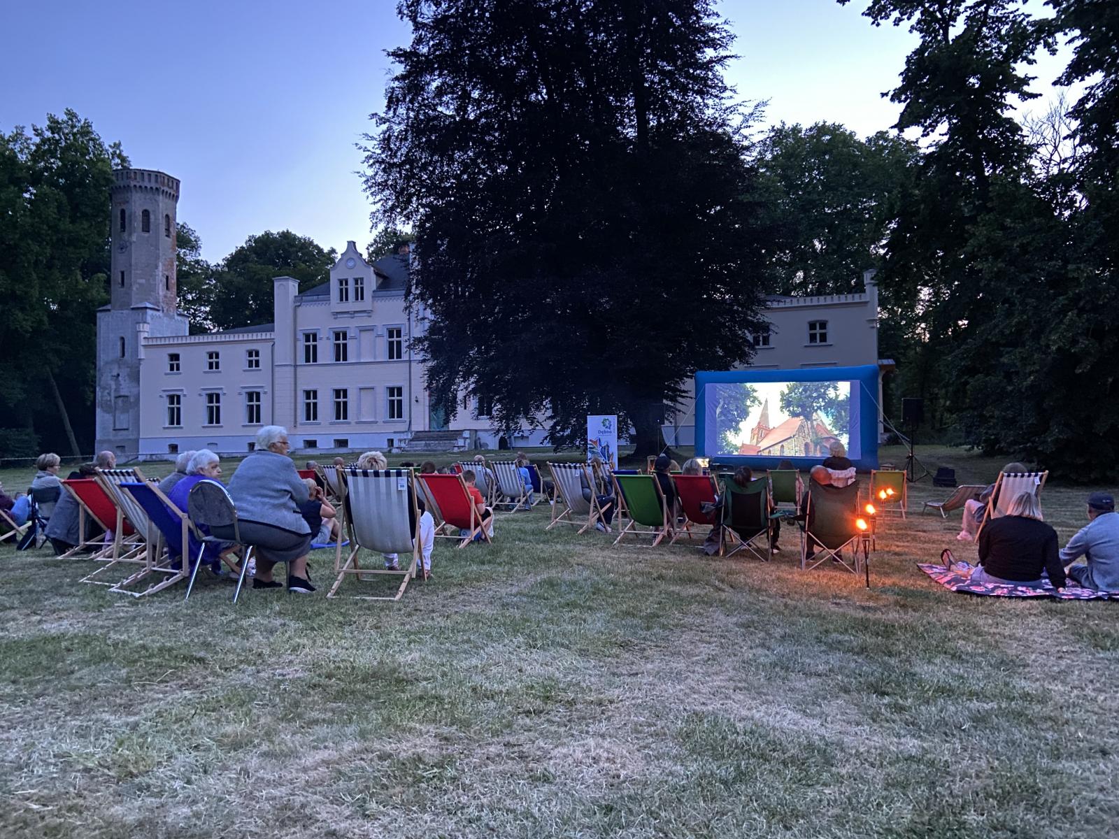 Widok na pałac w Dolsku i polane przed pałacem kino letnie ludzie na leżakach, 