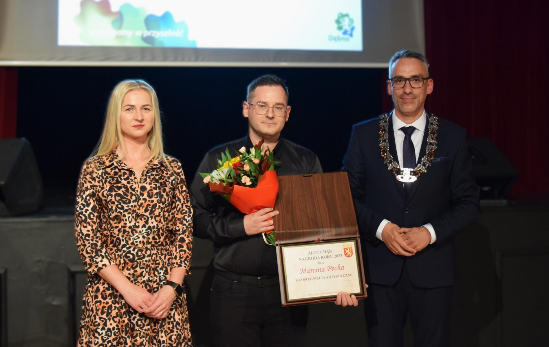 Stoją trzy osoby: od lewej kobieta, laureatka 2021 roku, w środku Marcin Pech, z prawej burmistrz Dębna